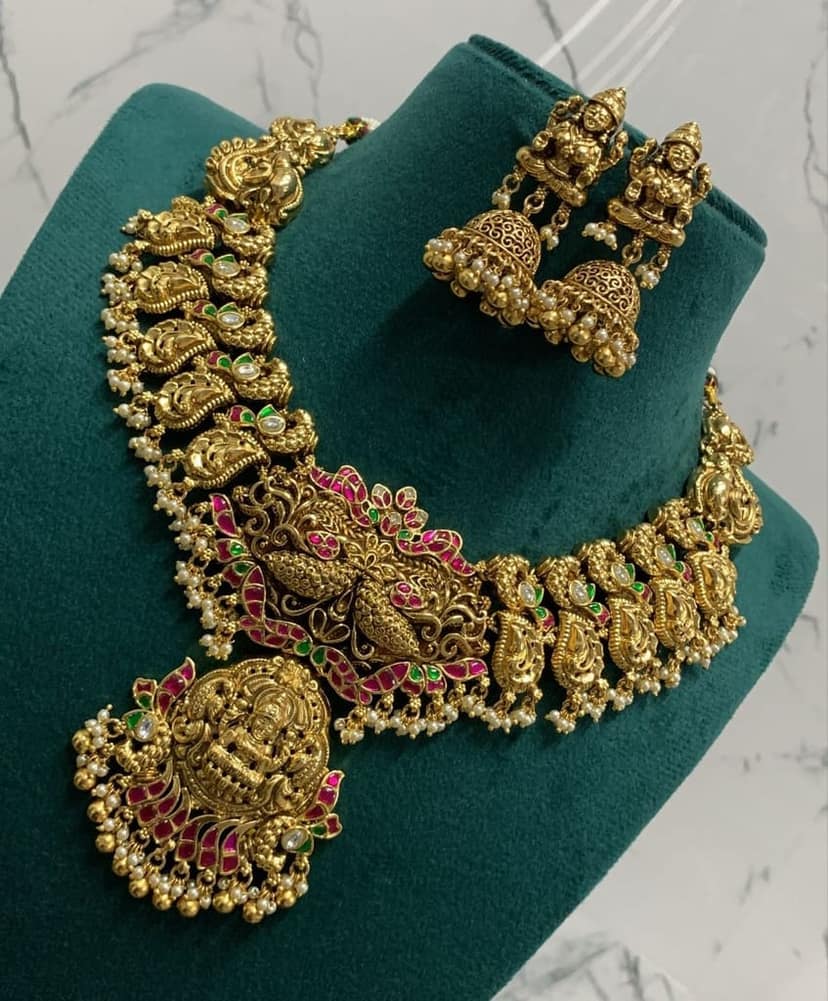 Stunning antique gold plated traditional Indian necklace set with intricate detailing and pink stones.
